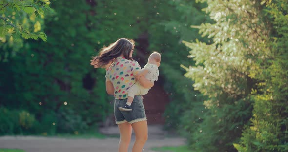 Young Beautiful Mother Carries Her Little Son in Her Arms and Spins with Him alt