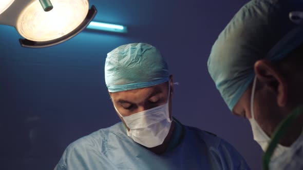 Doctor's Face in a Medical Uniform Makes an Operation in the Operating Room alt