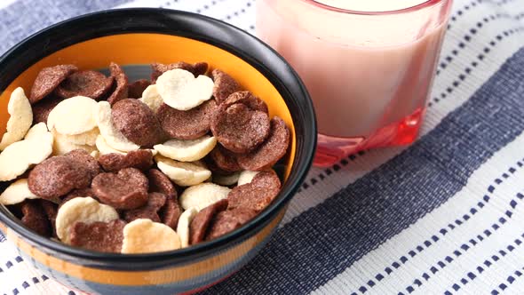 Top View of Chocolate Corn Flakes in a Bowl and Glass on Milk on Table alt
