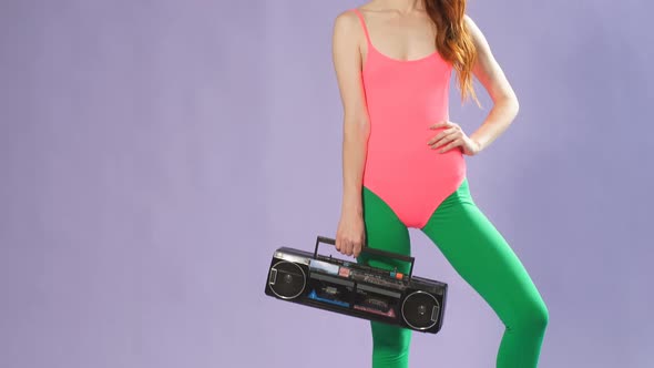 Selfconfident Young Female Fitness Trainer with Red Hair Holds in Hand Portable Audio Player Smiles alt