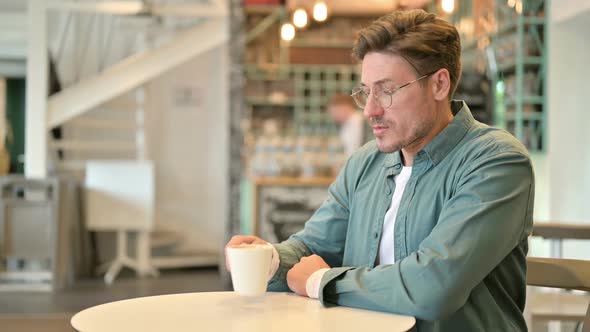 Relaxed Middle Aged Man Drinking Coffee in Cafe alt