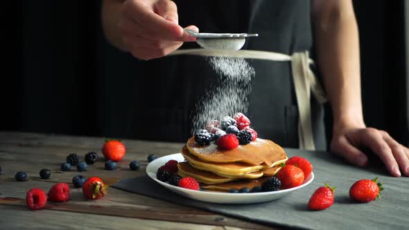 Sugar Powder Being Poured Over Pancakes Beautifully Served with Berries. Food Art