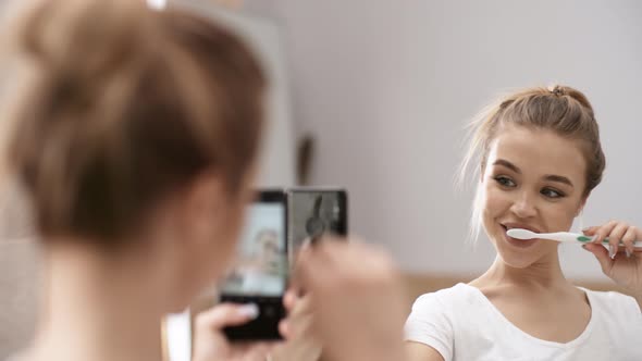 Lovely Caucasian Girl Taking Selfies with Toothbrush in front of Mirror alt