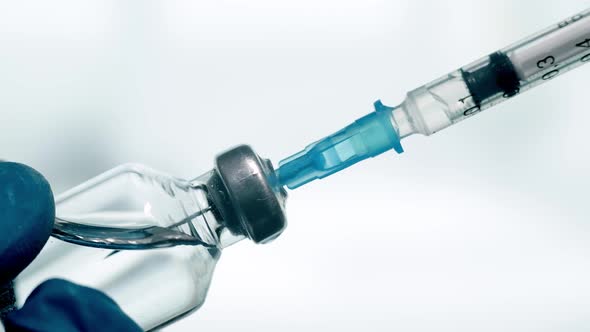 A Doctor is Drawing Up Vaccine From Phial Bottle and Filling Syringe Injection for Vaccination