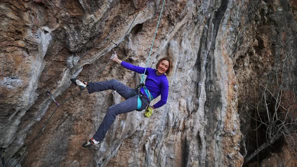 Slow Motion Smiling Tired Woman Rock Climber Hanging on Rope on Hard Challenge Route on Overhanging alt