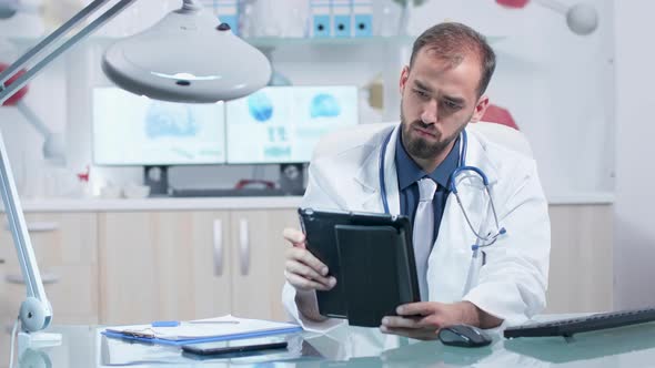 Concentrated Researcher in Modern Office Looking at Tablet PC alt