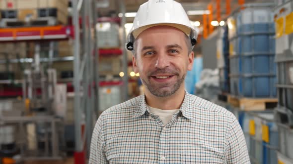 Portrait of Industrial Worker in Safety Hardhat Smiling at Camera in Warehouse alt