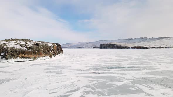 Baikal Lake Landscape with Cracked Frozen Ice Surface Covered with Snow in Winter