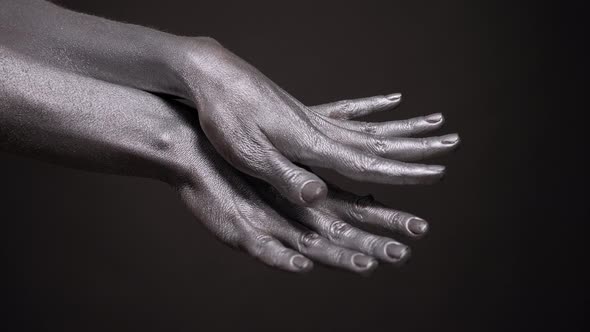 Closeup of a Woman with Silver Paint on Her Skin Slowly Moving Her Hands alt