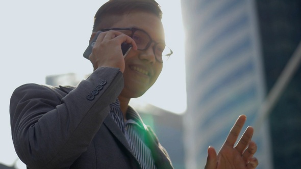 Portrait handsome Asian businessman talking phone with a friend in the urban city.