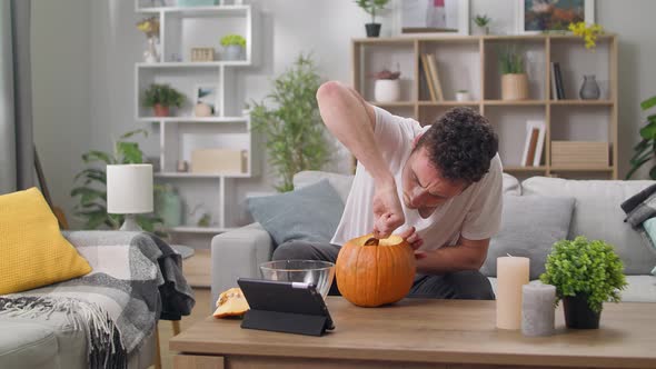 Young Man Extracts Seeds From Pumpkin with a Spoon alt