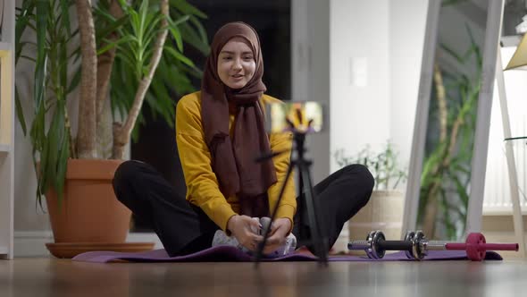 Confident Positive Yogi in Butterfly Pose Talking at Smartphone Training Indoors alt