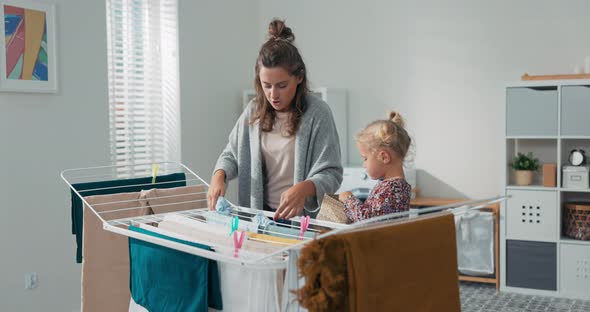 A Woman and Daughter are Doing Household Chores Putting Clean Clothes Out of the Washing Machine on alt