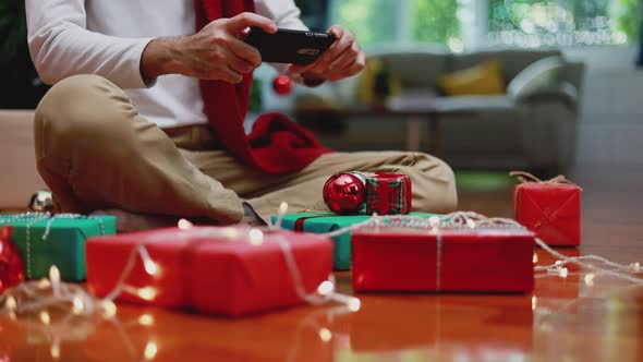 Asian man using mobile taking a photo gift box and upload to the internet in the living room.