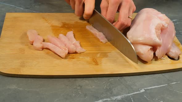 Knife Slices Chicken Breast Raw White Meat Fillet on Wooden Cut Board
