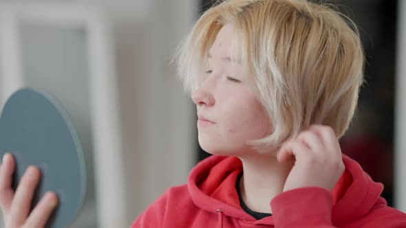 Closeup of Confident Teen Asian Girl Adjusting Makeup and Hair Looking in Hand Mirror alt