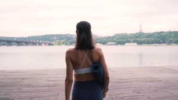 Girl Walking with a Fitness Mat By the Water