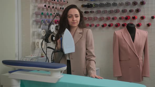 Female tailor are ironing clothes on ironing board with a iron steamer. Iron with steam alt