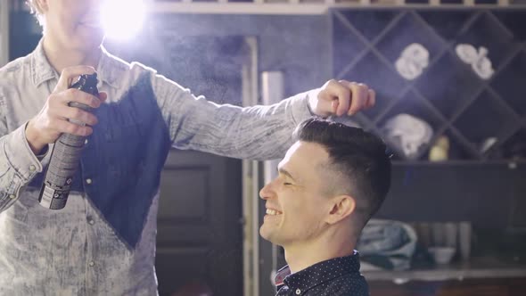 the Hairdresser Styling a Brunette Man and Spraying Hairspray in a Barbershop alt