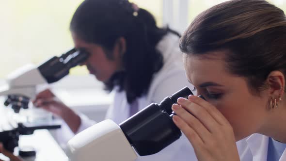 Scientists with Microscopes Working in Laboratory