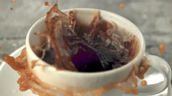 Super Slow Motion in a Mug of Coffee Drops a Piece of Sugar with Splashes alt