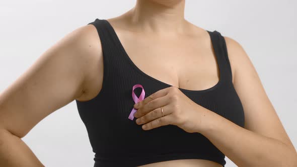 Caucasian Woman in a Black Seamless Bra Put with Her Hand Pink Ribbon for Breast Cancer