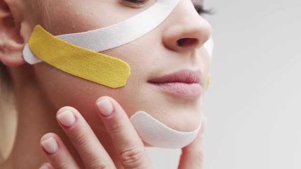Therapist is applying kinesio tape to female face. Kinesiology and recovery treatment. alt
