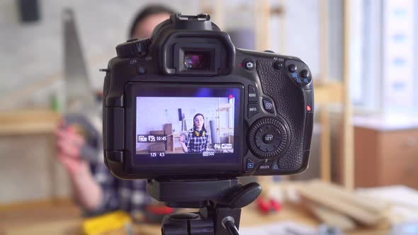 Young Beautiful Woman DIY Blogger Writes Video in Garage Workshop Using Hand Tool alt