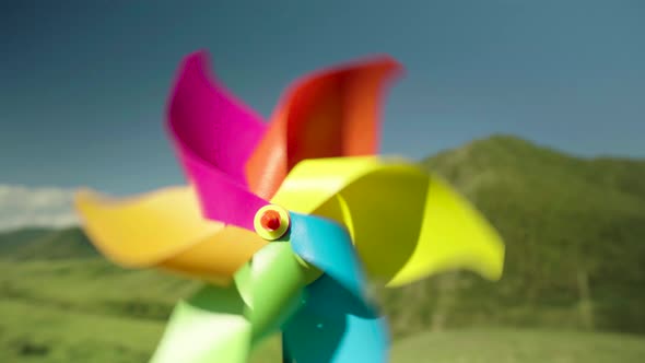 Mmulticolored Pinwheel Closeup is Spinning By Force of the Wind in Background of Green Mountains