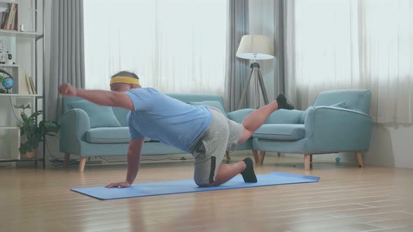 Fat Asian Man Doing Yoga In Balancing Table Pose On Mat  At Home alt