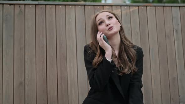 A Young Woman in Stylish Clothes and Long Hair is Talking on the Phone
