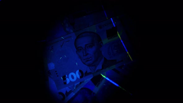 Ukrainian currency hryvnia in ultraviolet rays. The beam of the UV flashlight on the Banknotes