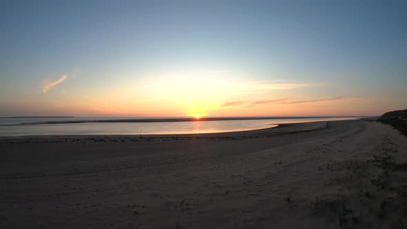 Aerial drone footage lifting from the beach and looking at the sun at the horizon of the sea. Beauti alt