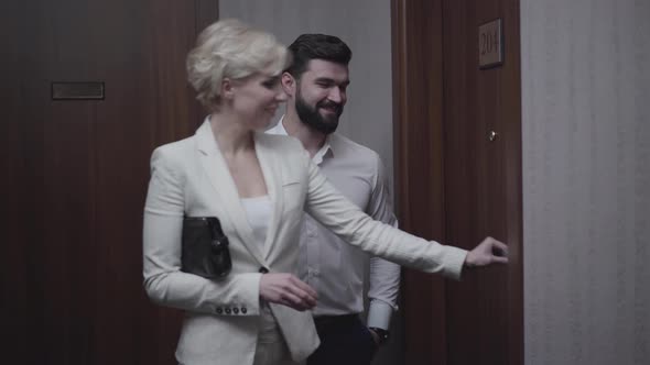 Side View of Smiling Young Caucasian Man and Woman Opening Room with Key Card and Entering alt