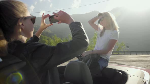 Beautiful Girls Take Photos on a Smartphone Inside a Red Convertible