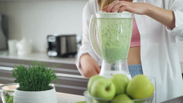 Female Prepares a Smoothies in the Kitchen Puts the Green Vegetables Ingredients and Mixes in a alt