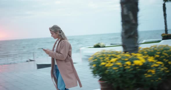 Blonde Woman Walks Along Embankment and Chats Via Phone