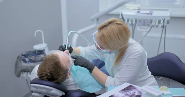 Dentist in Black Sterile Gloves Drills a Tooth in the Patient's Oral Cavity alt
