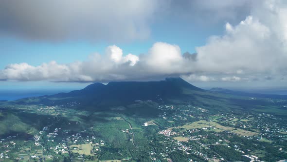 Drone camera moves over a city and rainforest near Nevis Peak in Saint Kitts and Nevis alt