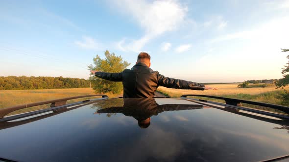 Young Guy Standing Out of Car Sunroof with Hands to Sides and Flying Like Plane While Riding Through alt