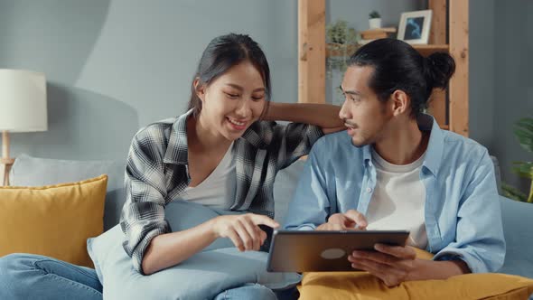 Happy asian young attractive couple man and woman use tablet online shopping furniture.