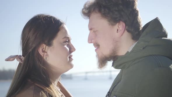Close-up of Smiling Caucasian Man with Nose Ring and Chubby Brunette Woman Rubbing Noses on River alt