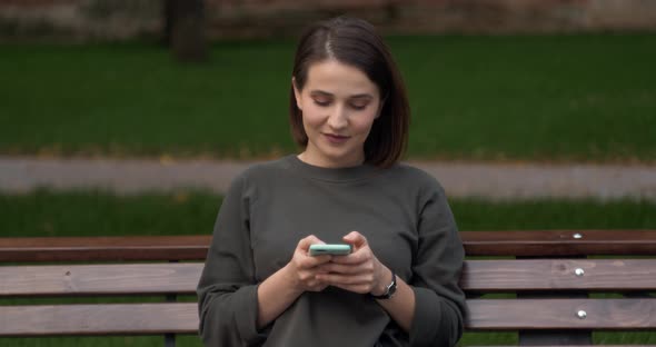 Happy Girl Using a Smart Phone Voice Recognition Audio Message Function on Line Walking on a Street alt