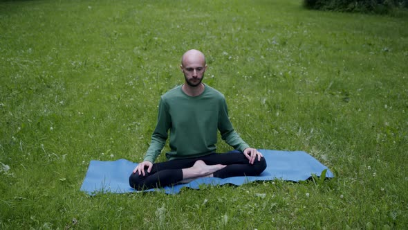 Man Does Yoga on the Lawn in His Own Garden Breathing Exercise in Lotus Position alt