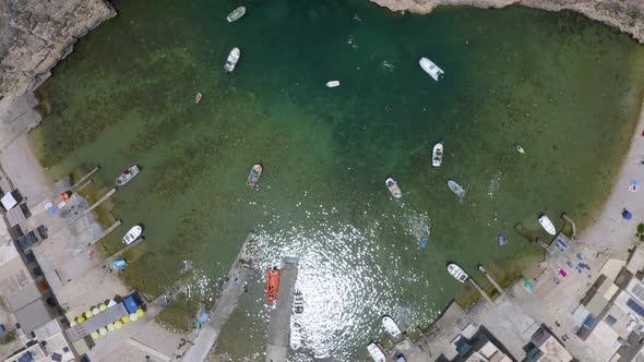 Boats in the sea bay of Dwerja cave port town,Malta,overhead aerial. alt