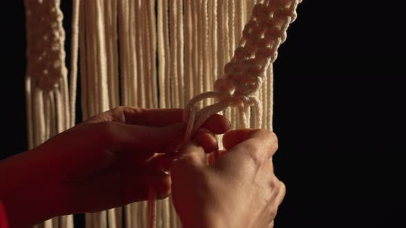 Women's Hands Weave a Macrame Pattern in Creative Workshop on Black Background alt
