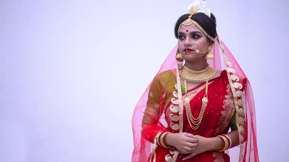Sad and unhappy Indian Bengali bride against a white wall alt