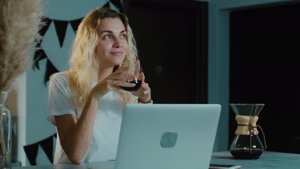Pretty Woman working at laptop and drinking black coffee in cafe. alt