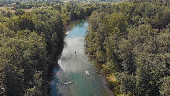 People Sailing on Boats Down the River Between the Forest alt