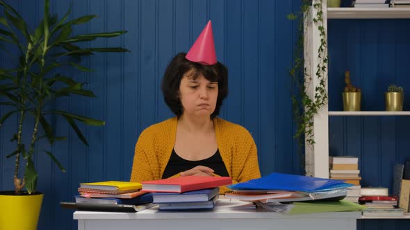 Sad Lonely Business Woman Sitting at Workplace Alone with a Birthday Hat and Celebrating Her
